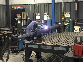 worker welding a pipe in a manufacturing workspace