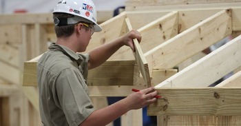 worker in a hardhat making a wood structure