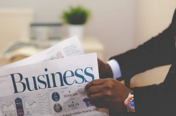 man holding a newspaper titled business